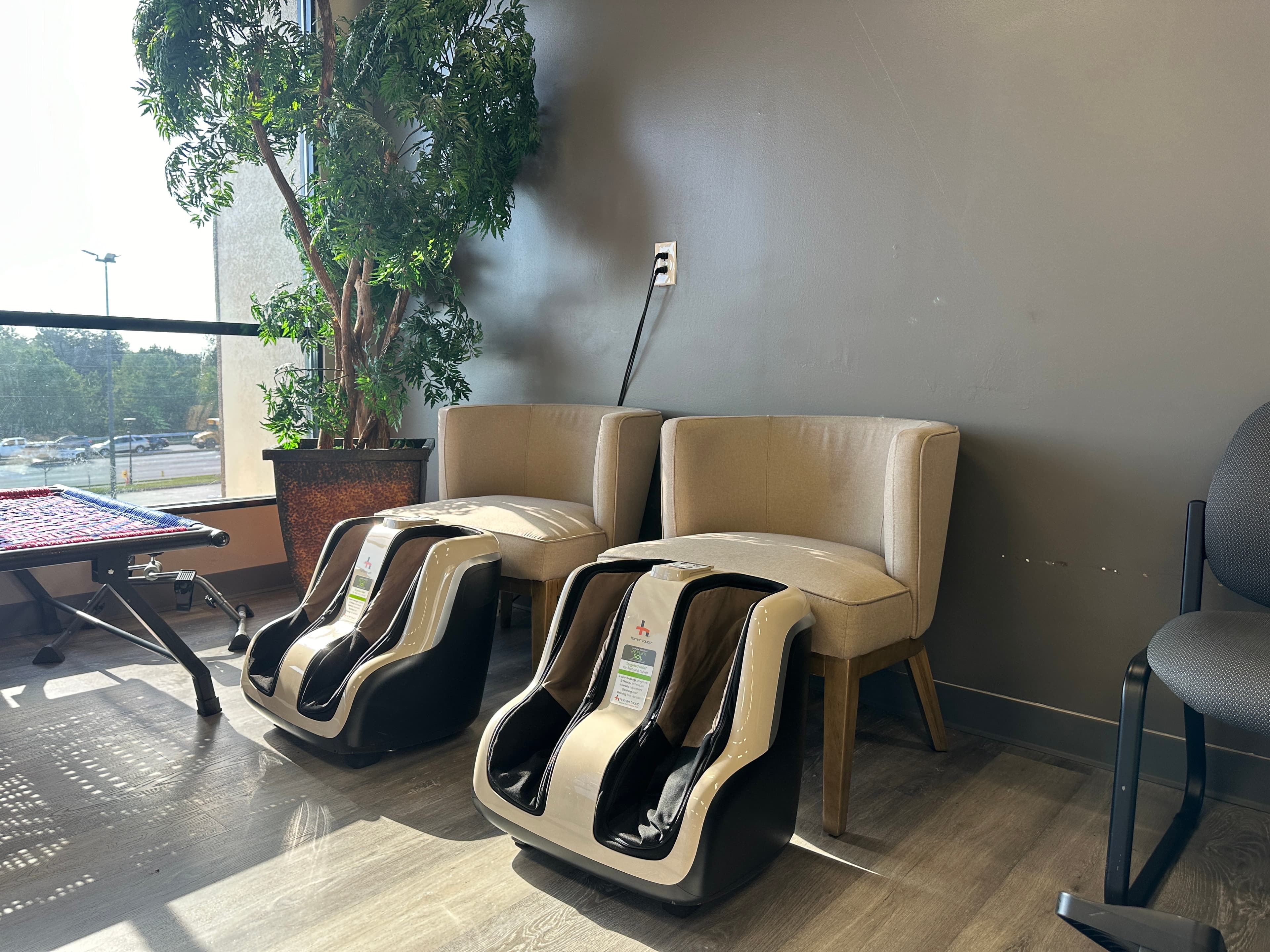 Massage chairs lined up beside a window with treetop views
